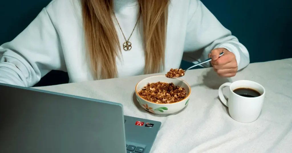 Mulher fazendo uma refeição mexendo no computador