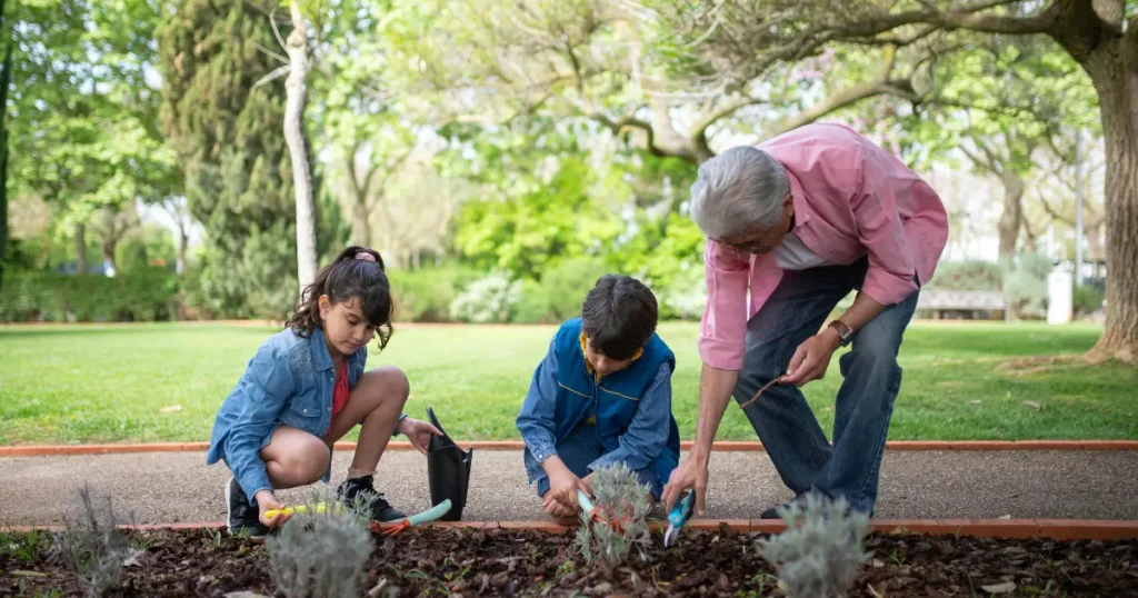 Duas crianças e uma adulto no jardim mexendo com plantas