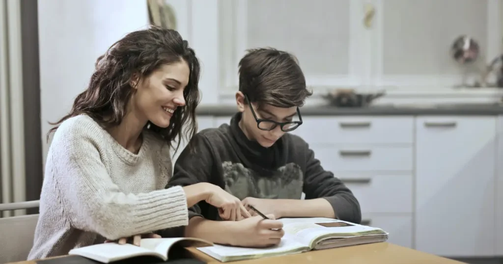Mulher ajudando um menino a estudar