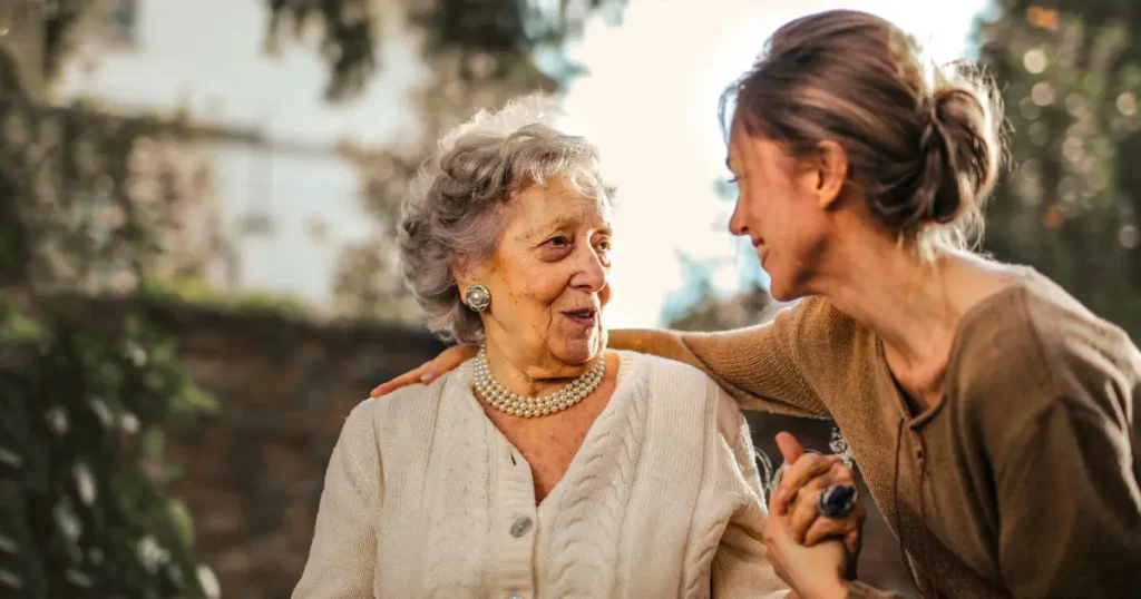Duas mulheres sentadas sorrindo e olhando uma para outra