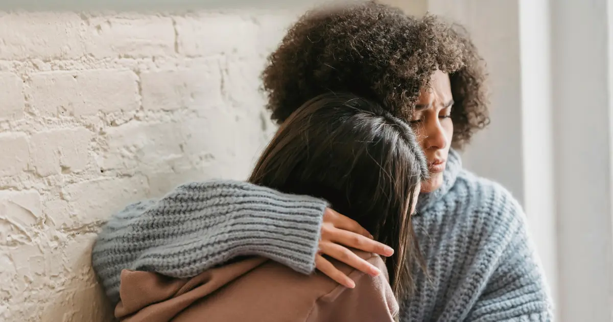 Duas mulheres se abraçando com semblante triste