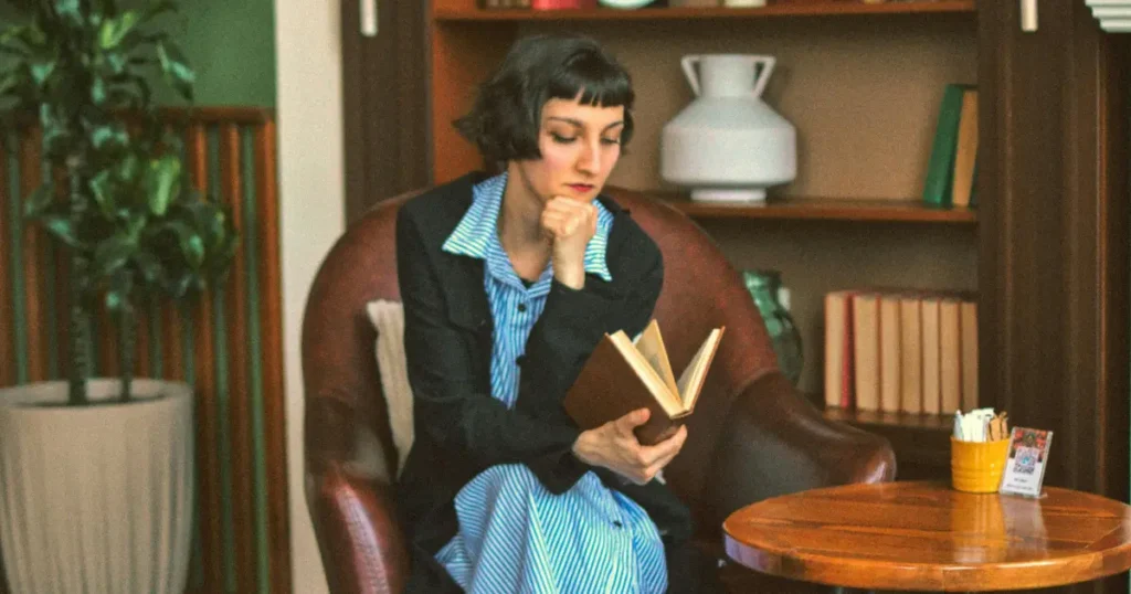 Mulher em uma poltrona olhando para um livro