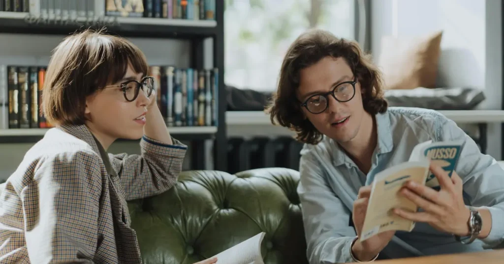 Um homem mostrando um página de um livro para uma mulher